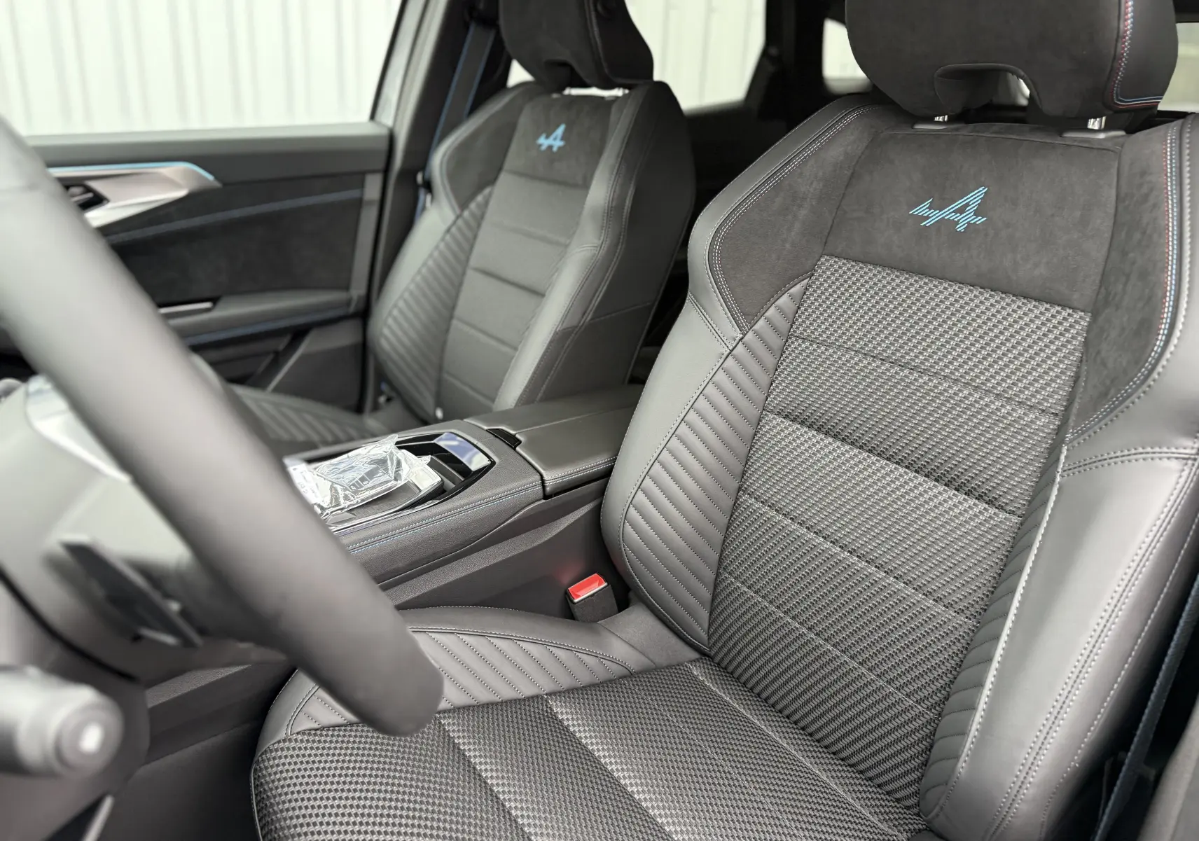 Vue intérieure rapprochée des sièges avant gris avec logo Alpine bleu sur une Renault Austral 2025 finition Esprit Alpine.