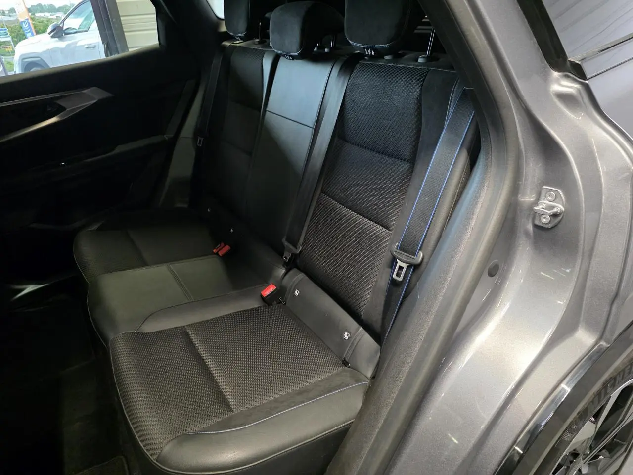 Vue côté droit de la banquette arrière noire avec surpiqûres bleues du Renault Austral gris foncé 2024.