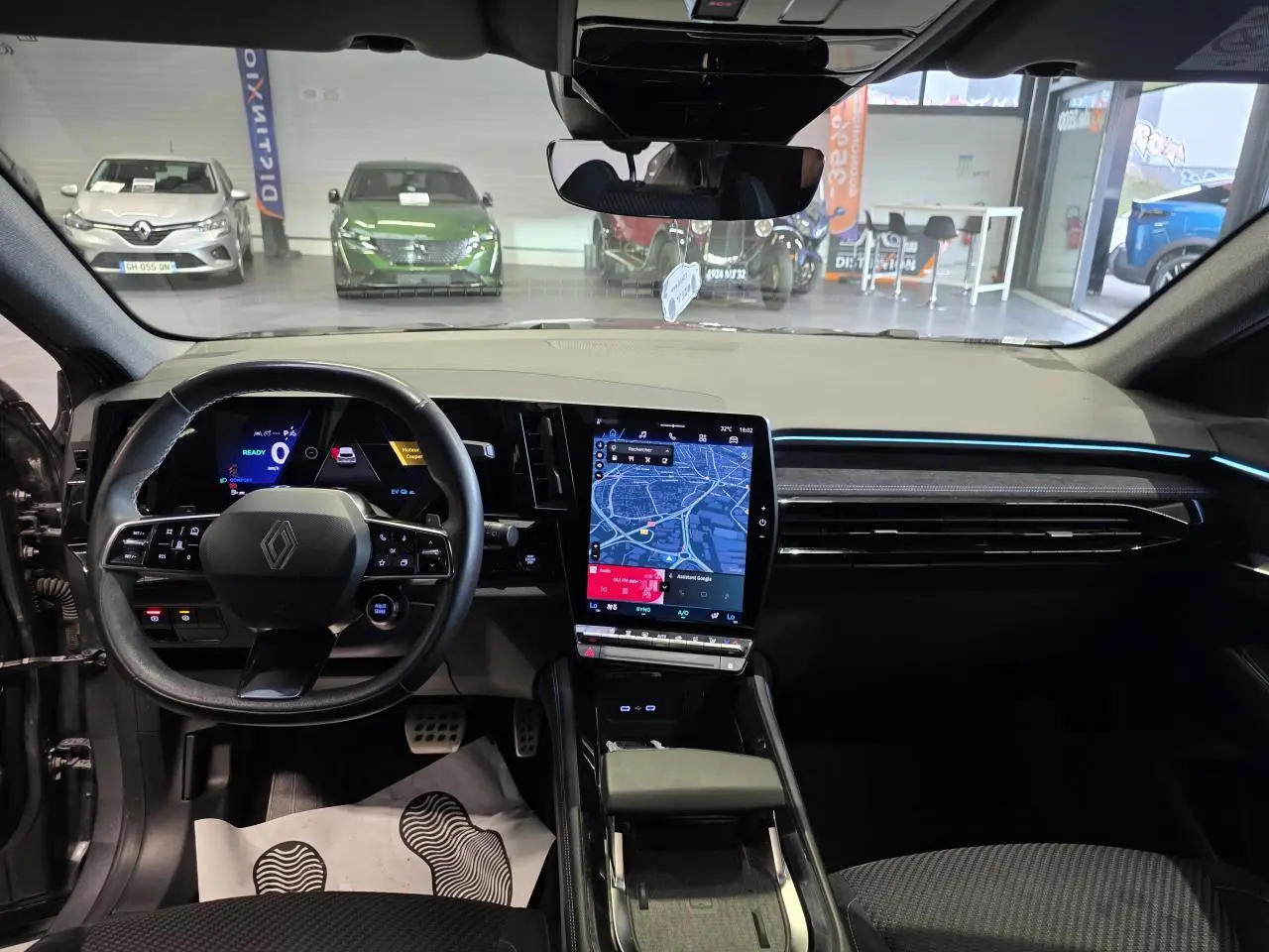 Vue intérieure avant du Renault Austral gris foncé, avec tableau de bord digital et écran tactile central vertical.