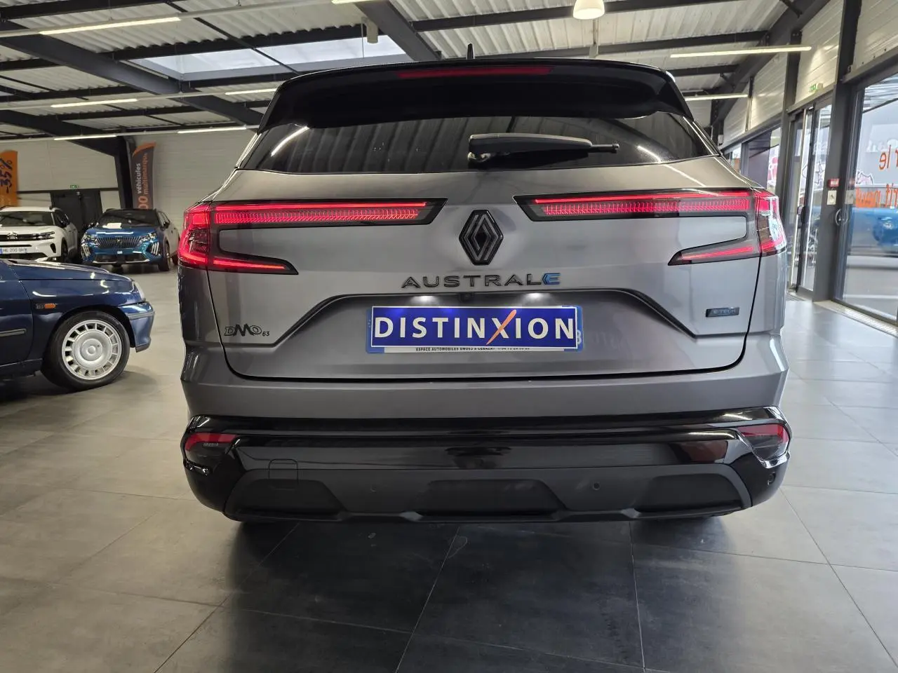 Vue arrière d'un Renault Austral gris foncé avec feux LED allumés et logo distinctif en concession.