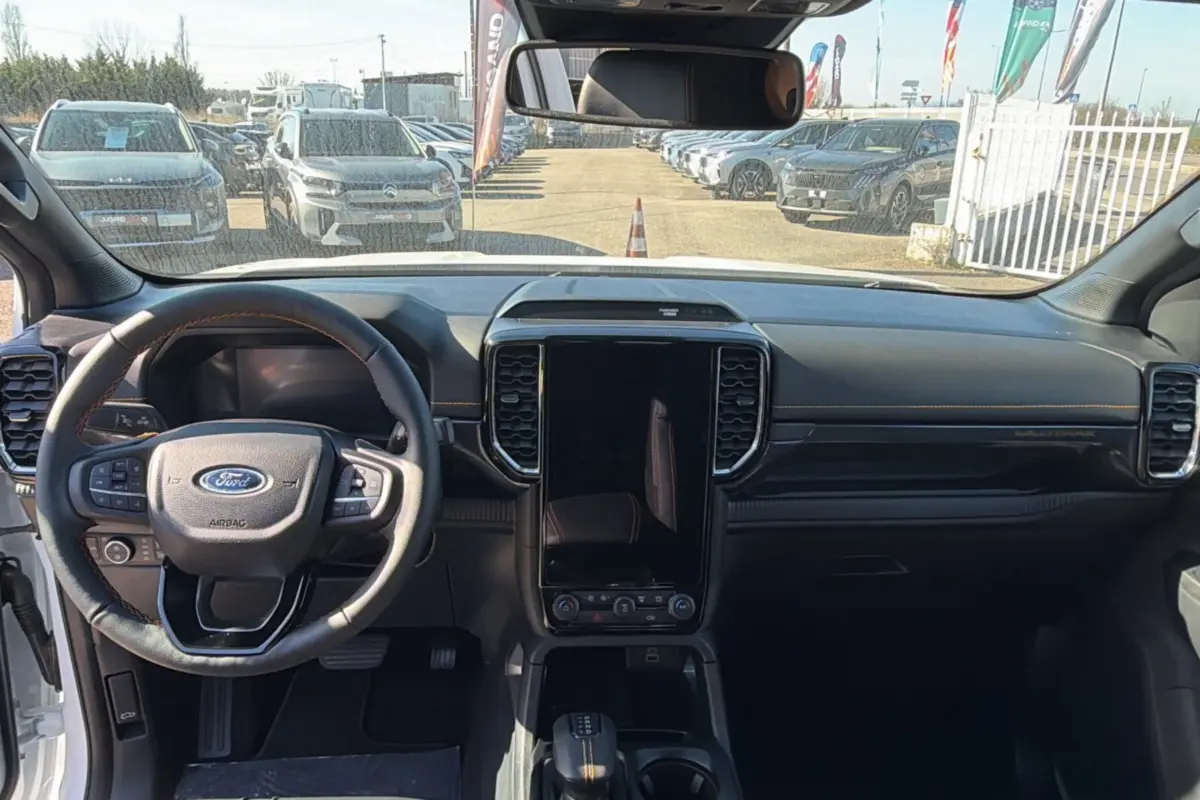 Vue intérieure frontale du Ford Ranger Wildtrak 2025, avec tableau de bord noir et grand écran tactile vertical central.