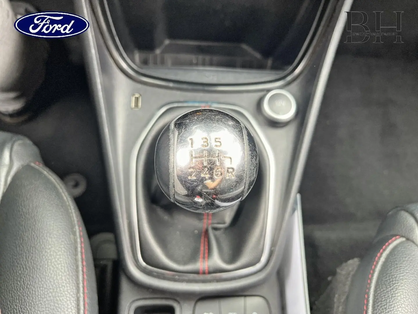 Gros plan sur le levier de vitesses manuel chromé avec surpiqûres rouges, intérieur cuir noir du Ford Puma 2020.