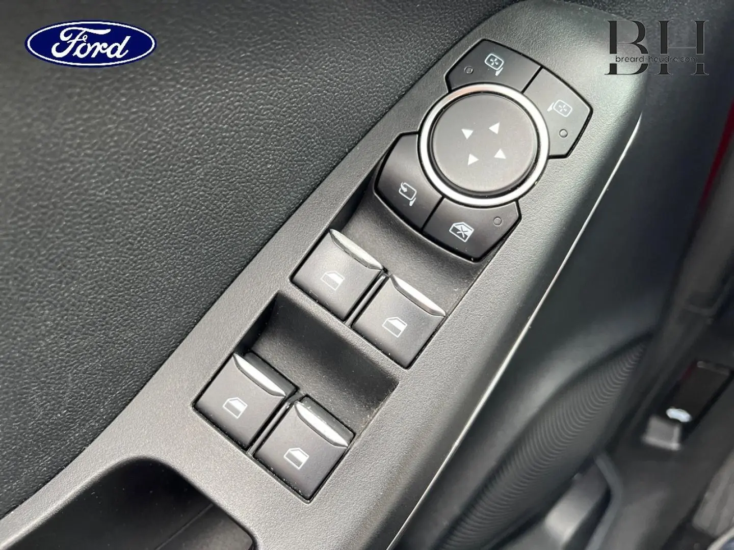 Gros plan sur les commandes des vitres et rétroviseurs côté conducteur d'une Ford Puma rouge Premium Lucid.