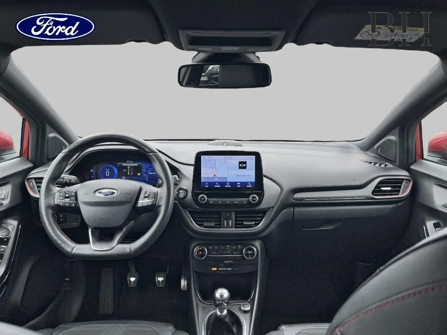 Vue intérieure avant du Ford Puma 2020, tableau de bord noir avec écran tactile central et volant multifonction cuir.