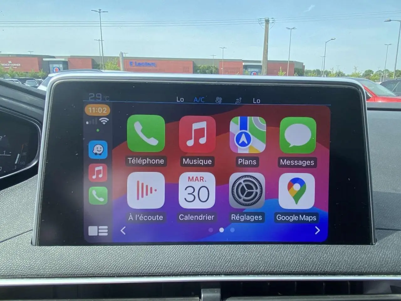 Écran tactile central du Peugeot 3008 blanc 2018 affichant les applications Apple CarPlay en plein jour.