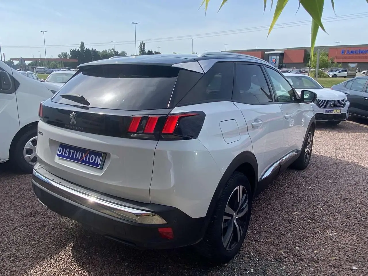 Peugeot 3008 blanc nacré vue 3/4 arrière droit avec toit noir et vitres surteintées sur parking.
