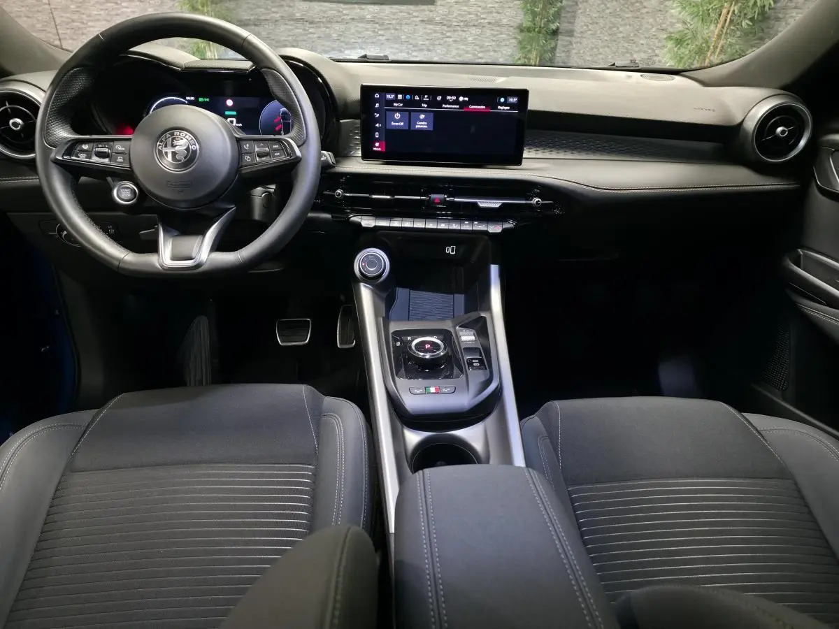 Vue intérieure avant de l'Alfa Romeo Tonale 2025 bleu, volant cuir sport et écran tactile central large.