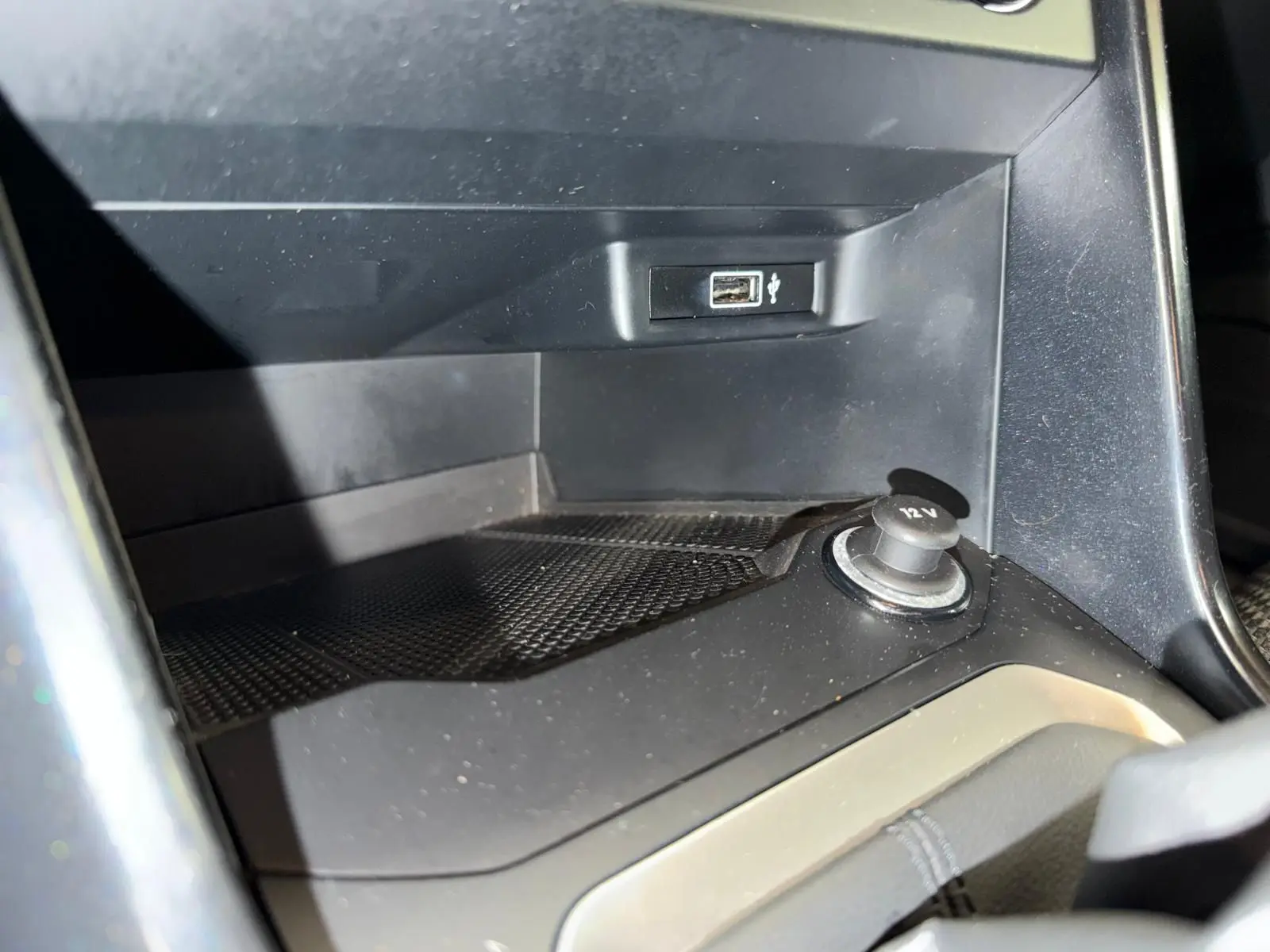 Gros plan intérieur sur la prise 12V et port USB du Volkswagen T-Roc bleu, version 1.0 TSI 115 Lounge.