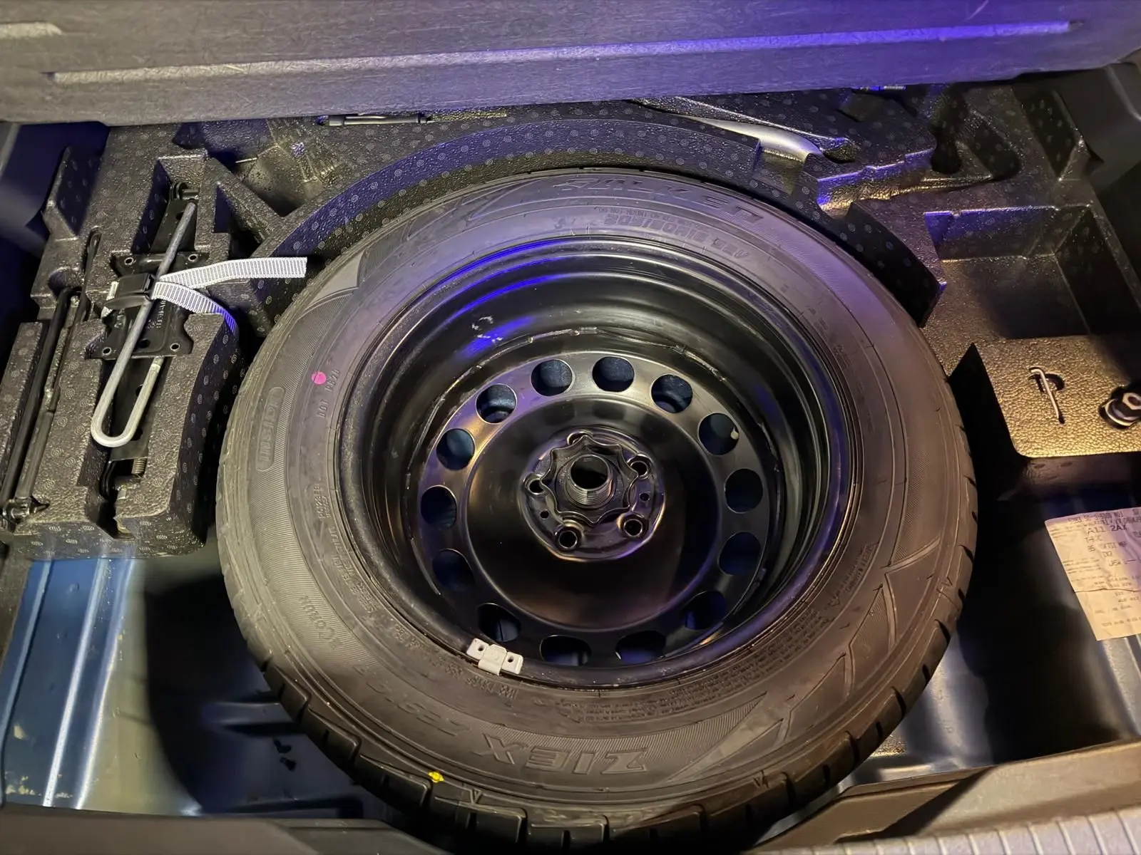 Vue rapprochée de la roue de secours noire dans le coffre d’un Volkswagen T-Roc bleu 2019.