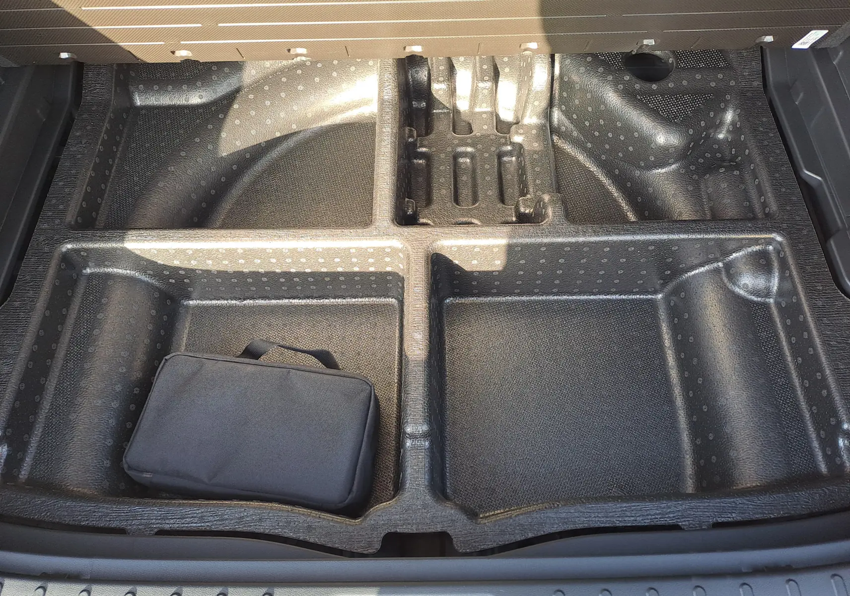 Rangement sous le coffre du Hyundai Tucson 2025 en Abyss Black, compartiments modulables avec trousse noire visible.