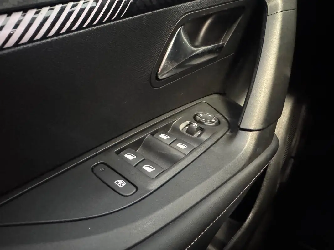 Gros plan sur la commande des vitres électriques côté gauche de la porte intérieure noire du Peugeot 2008 Hybrid 145 e-DCS6 Allure.