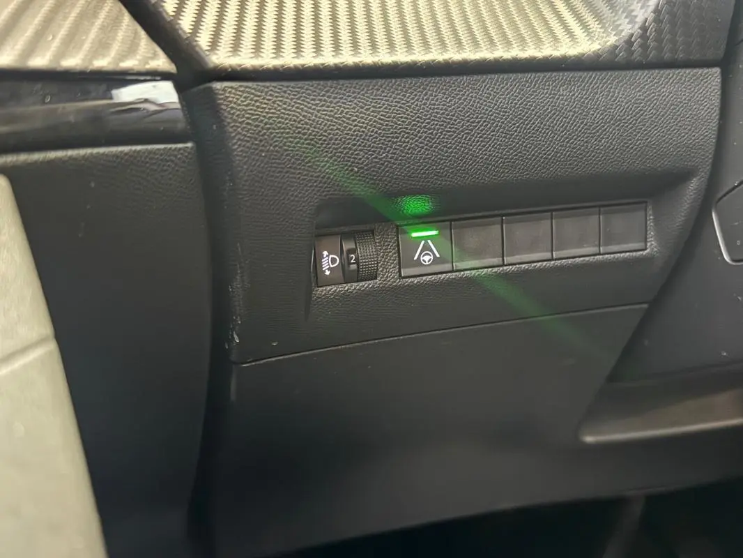Gros plan sur les commandes latérales gauche du tableau de bord noir du Peugeot 2008 Hybrid 145 e-DCS6 Allure 2025.