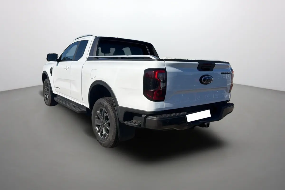 Ford Ranger 2.0 205 Wildtrak Supercab blanc pur vu en 3/4 arrière droit avec attelage et barres de toit.