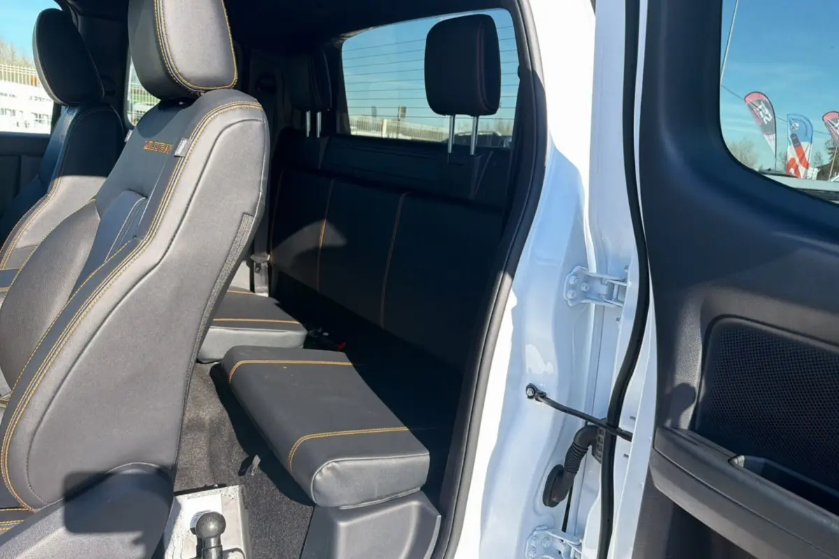 Vue intérieure côté droit du Ford Ranger blanc 2025, montrant les sièges arrière et avant avec surpiqûres orange.