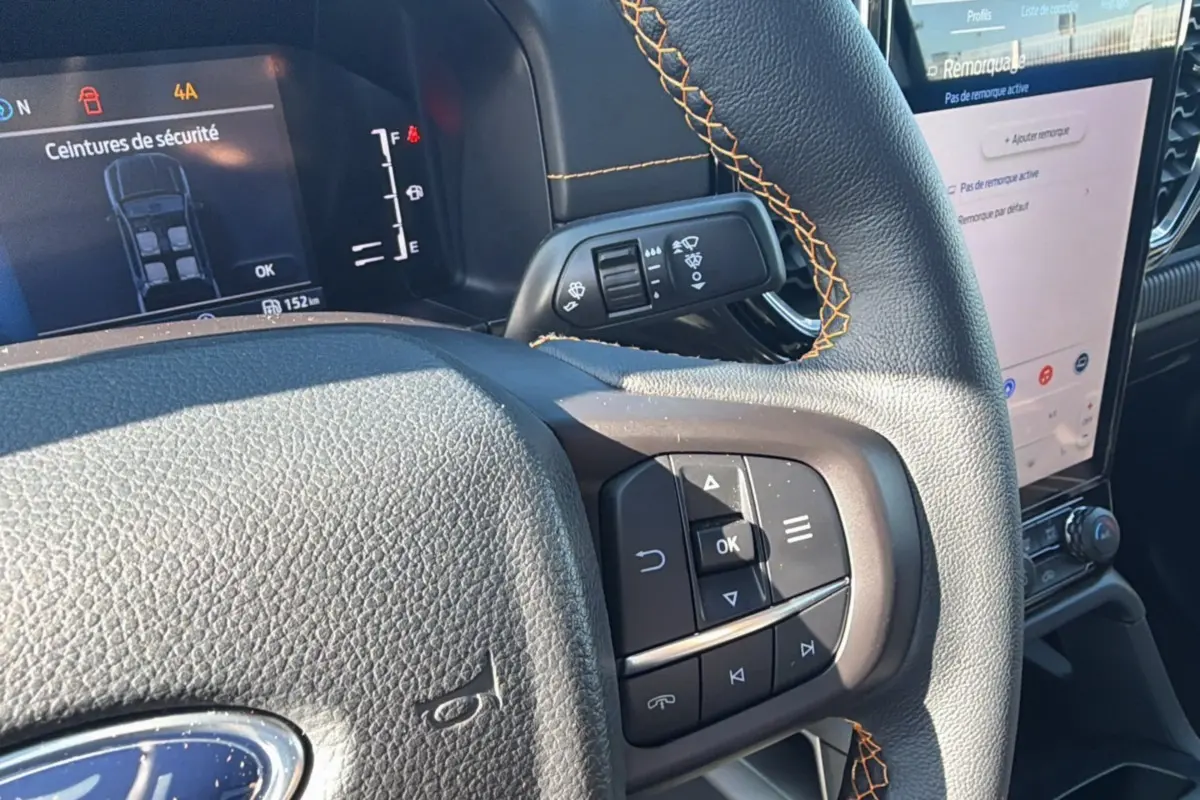 Gros plan sur le volant cuir noir avec surpiqûres orange et commandes multifonctions du Ford Ranger Wildtrak 2025.