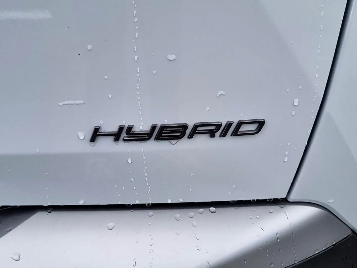 Gros plan sur l’inscription « Hybrid » noire sur la partie arrière blanche d’un Peugeot 3008 toit noir.