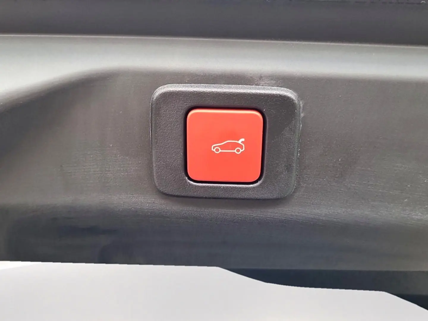 Bouton rouge de fermeture électrique du hayon sur un Peugeot 3008 blanc toit noir, vue en gros plan.