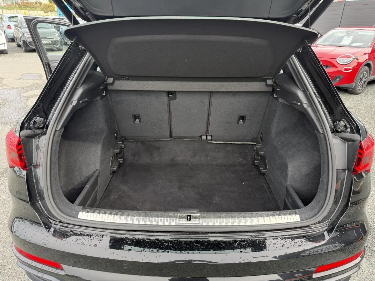 Coffre ouvert vu de l'arrière d'un Audi Q3 noir 2019 avec seuil de chargement en acier inoxydable.