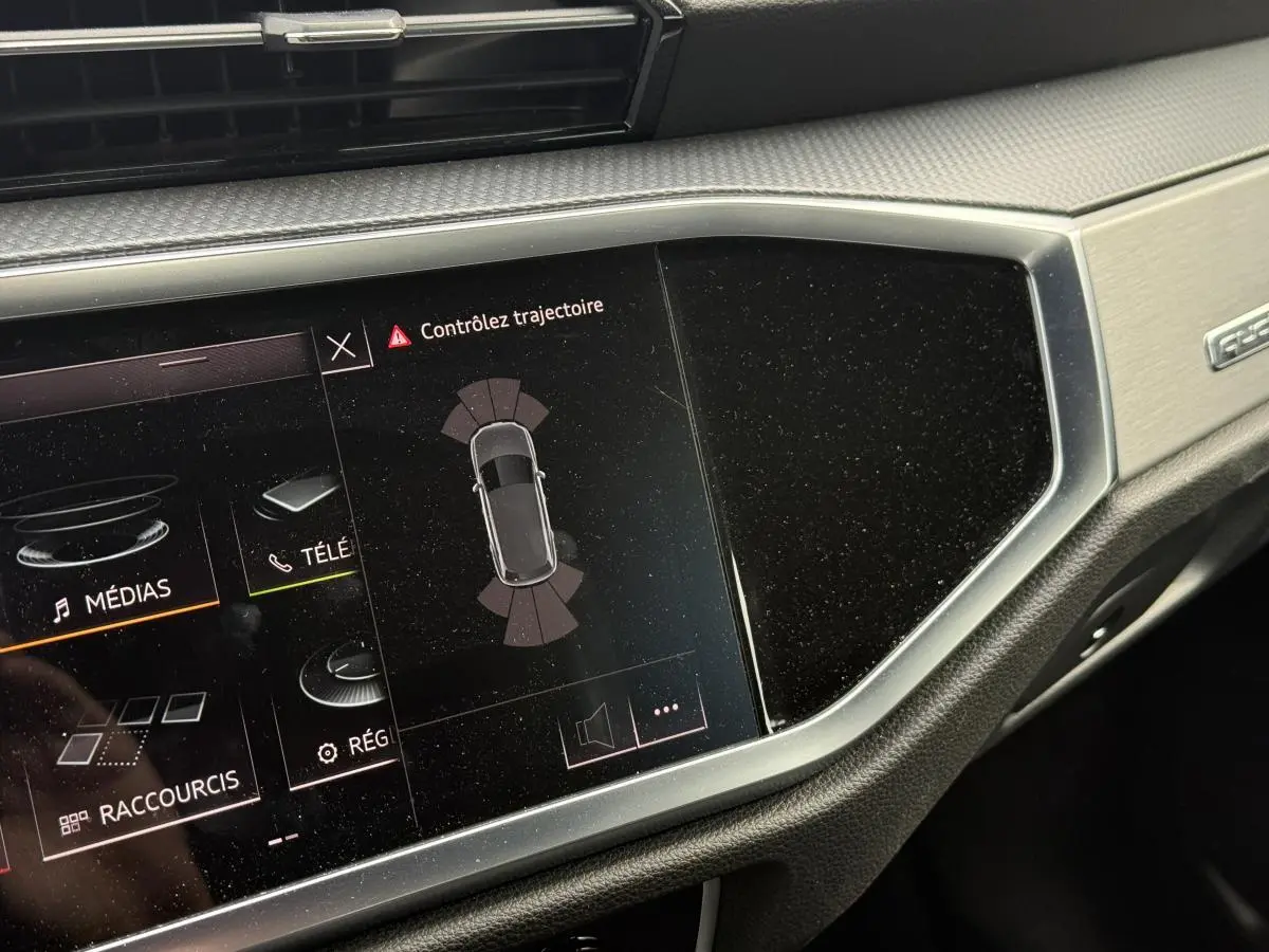 Écran tactile central de l'Audi Q3 S Line 2019 affichant l'alerte de contrôle de trajectoire, avec décor aluminium brossé.