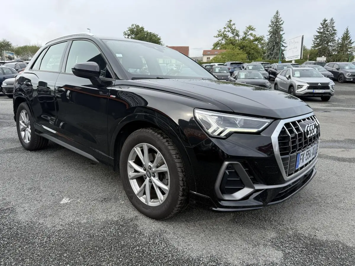 Audi Q3 noir vue 3/4 avant droit, calandre chromée et phares LED distinctifs sur parking extérieur.