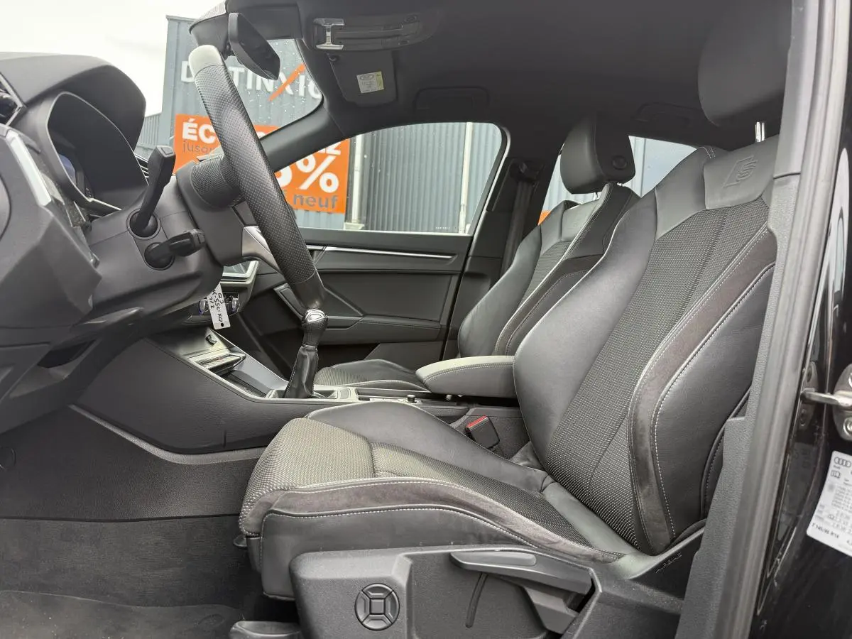 Intérieur noir de l'Audi Q3 S Line 2019 vu côté gauche, avec sièges sport en tissu et similicuir et volant cuir.