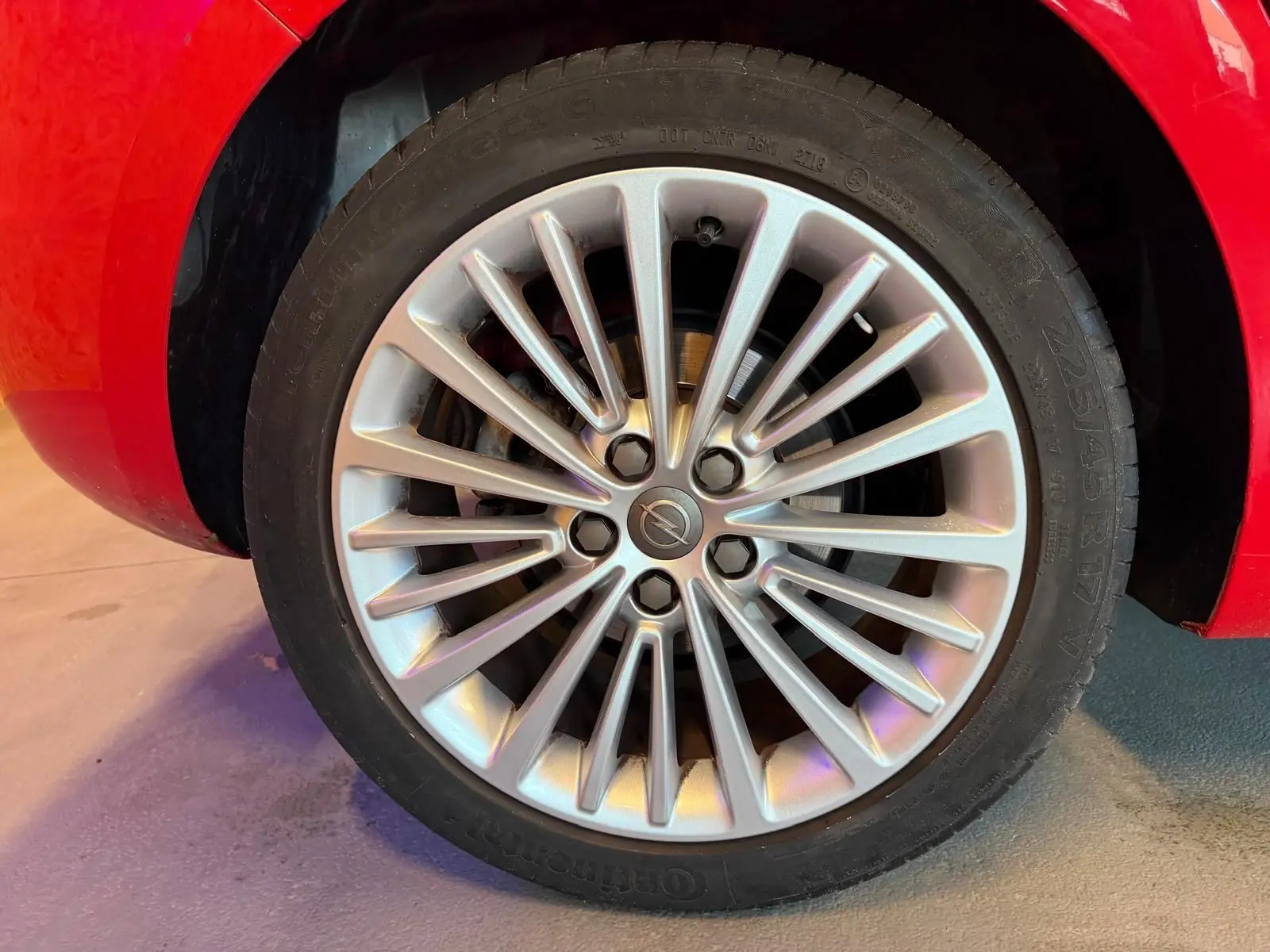 Gros plan sur la jante alu argentée de l'Opel Astra rouge, mettant en valeur le logo central Opel.