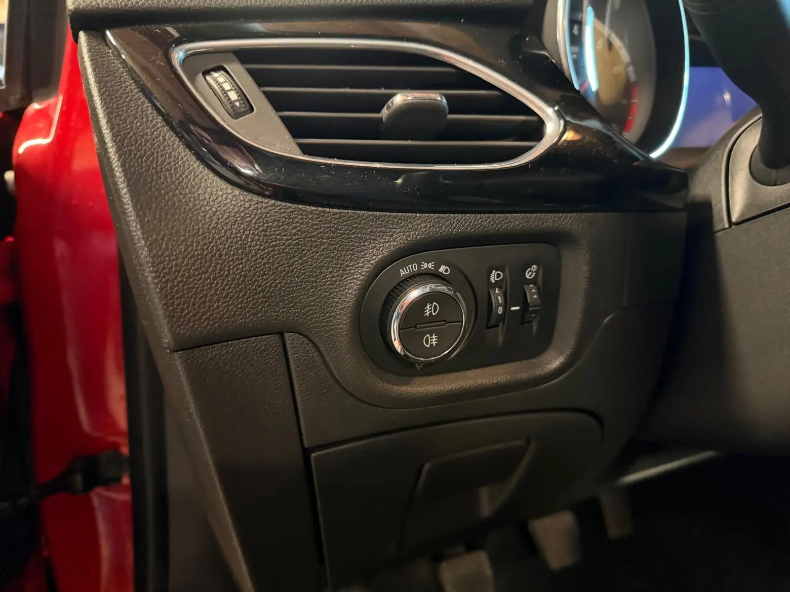 Gros plan sur la commande des phares et aérateur côté gauche d’un Opel Astra rouge 2016.
