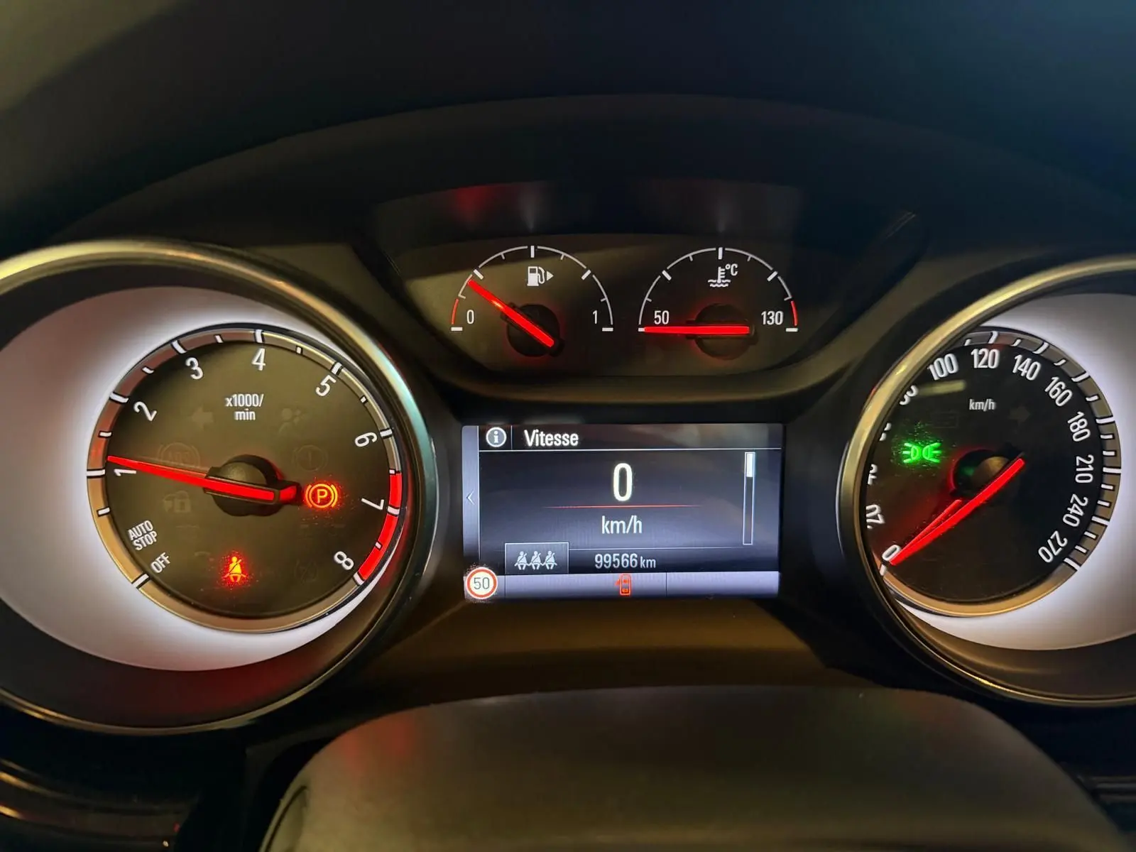 Vue rapprochée du tableau de bord de l'Opel Astra rouge, affichant le compteur et l'ordinateur de bord à 0 km/h.