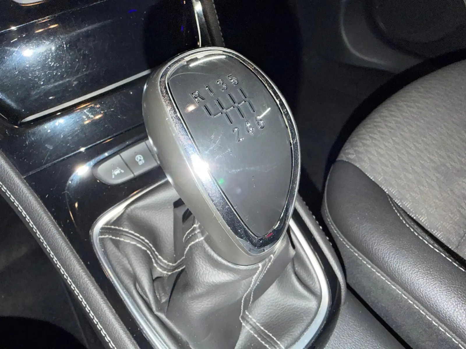 Gros plan sur le levier de vitesses manuel gris et noir de l’Opel Astra 1.4i Turbo 125 Innovation, intérieur sombre.