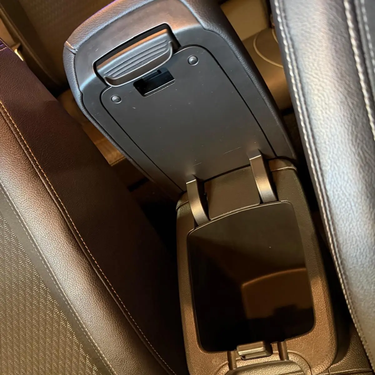 Vue rapprochée de l'accoudoir central ouvert en cuir noir entre les sièges avant de l'Opel Astra rouge.