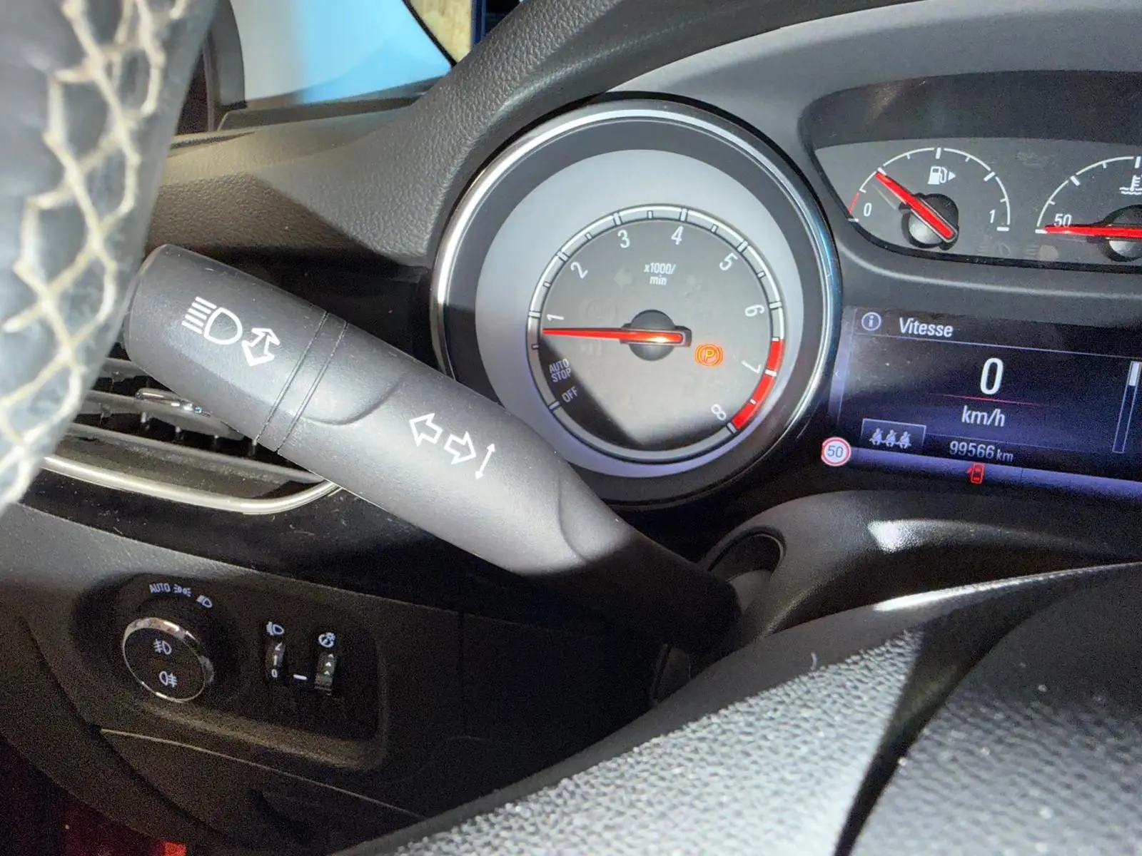 Vue rapprochée du tableau de bord de l'Opel Astra rouge 2016, montrant le compteur et le commodo des phares.