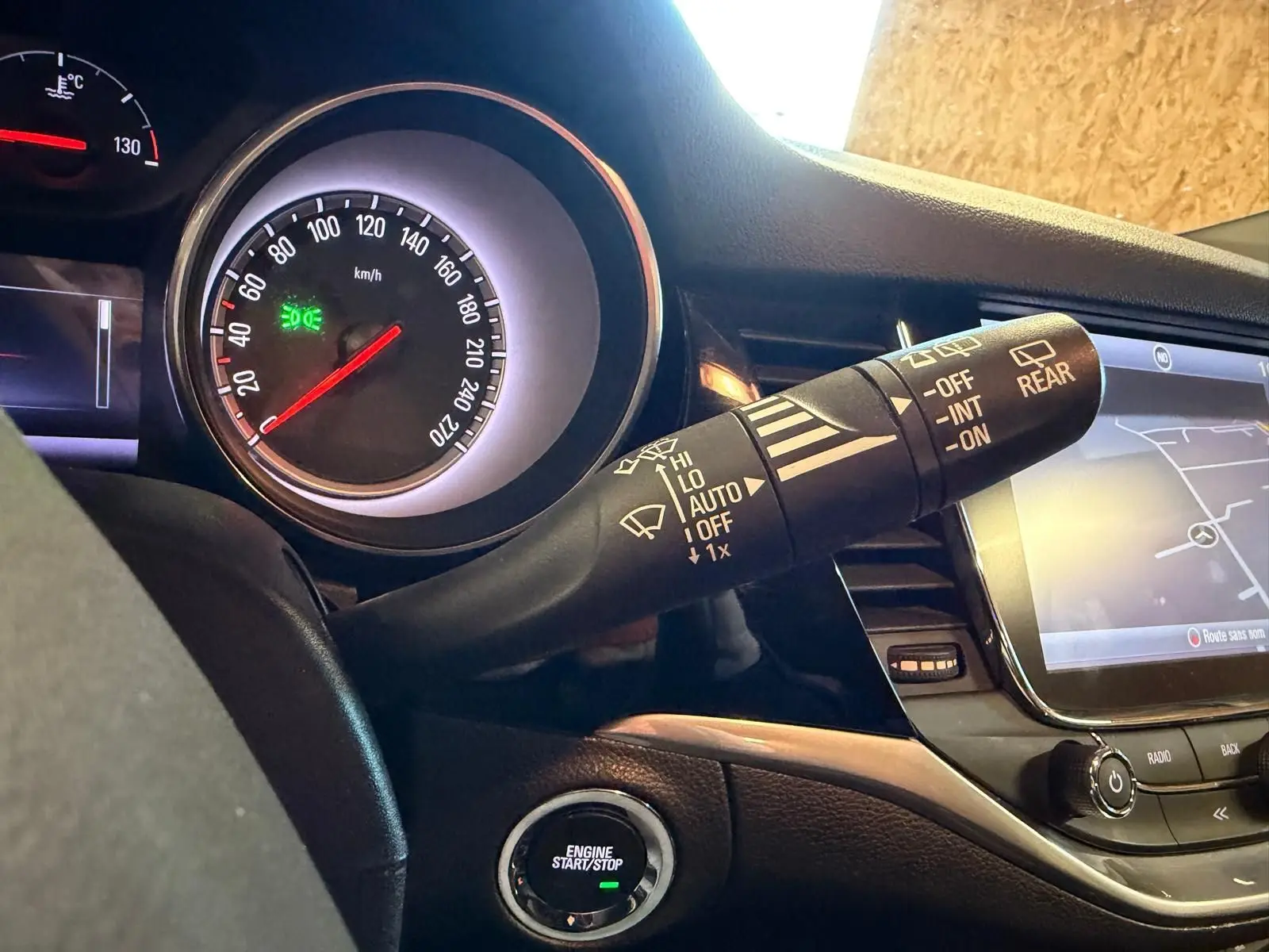 Vue rapprochée du tableau de bord de l’Opel Astra 2016, montrant le compteur, le bouton start/stop et l’écran tactile.