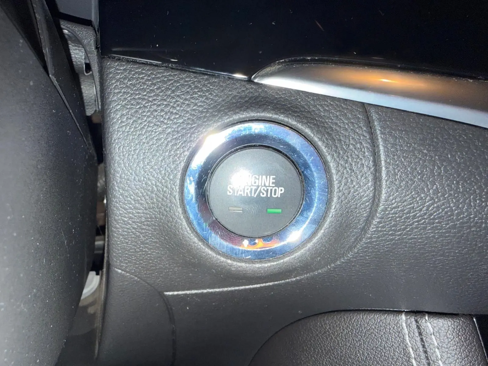 Gros plan sur le bouton start/stop entouré de chrome dans l’habitacle noir de l’Opel Astra rouge.