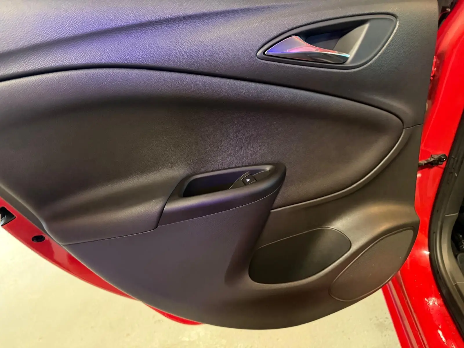Vue intérieure du panneau de porte avant gauche noir sur Opel Astra rouge de 2016.