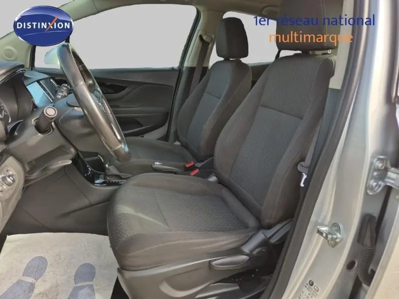 Vue intérieure côté conducteur de l'Opel Mokka X 2018 avec sièges tissu noirs et volant multifonction cuir.