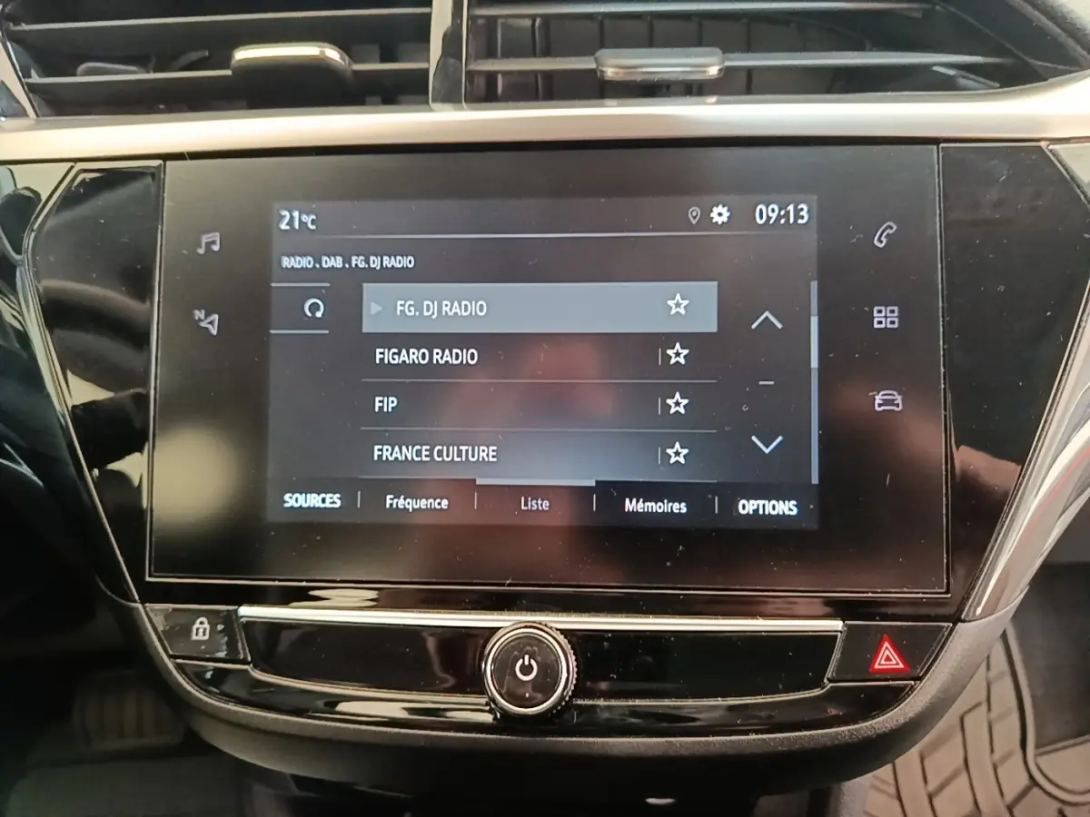 Écran tactile central de l’Opel Corsa blanc 2022 affichant la liste des radios, vue rapprochée intérieure.