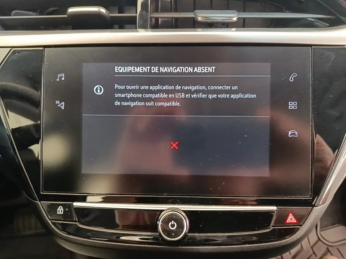 Écran tactile central de la console d’une Opel Corsa blanche, affichant un message d’équipement de navigation absent.