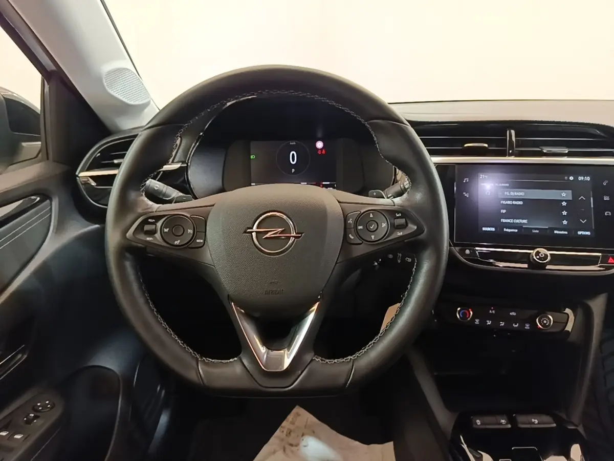 Vue intérieure centrée sur le volant cuir multifonctions noir de l’Opel Corsa avec tableau de bord digital et écran tactile.