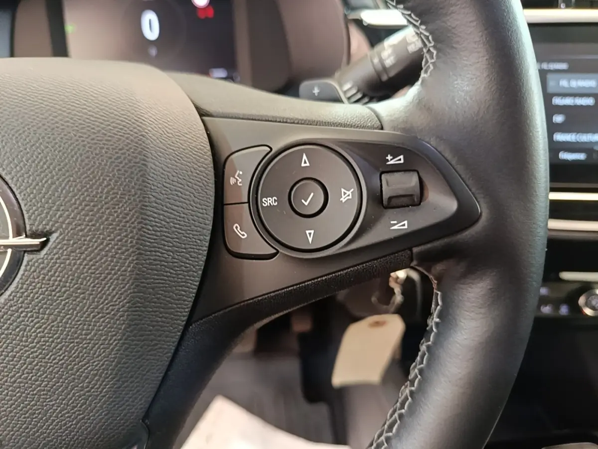 Gros plan sur le volant cuir multifonctions de l'Opel Corsa 2022, avec commandes audio et téléphone intégrées.