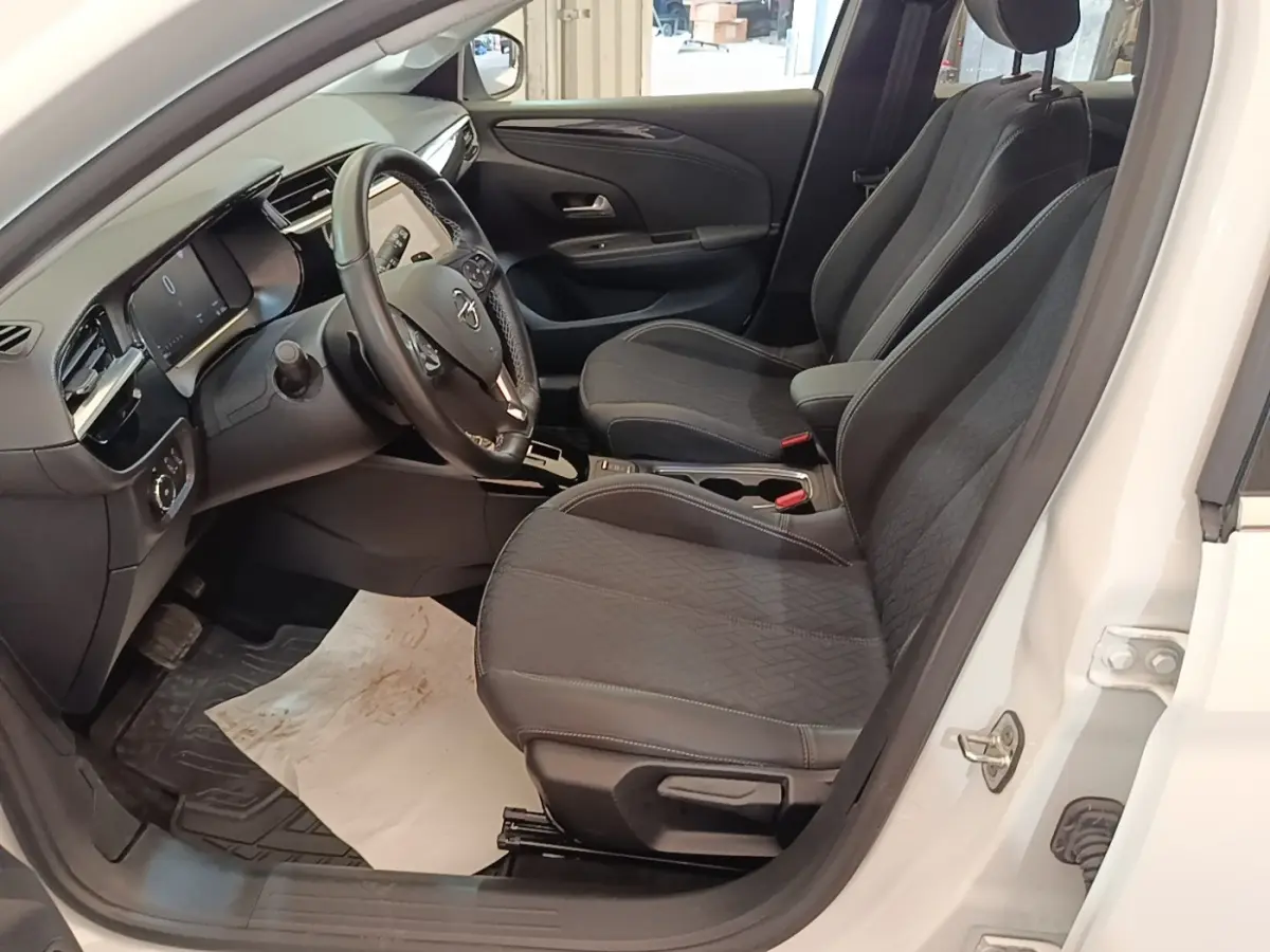 Vue intérieure côté conducteur d'une Opel Corsa blanche 2022, volant cuir multifonctions et sièges tissu noirs.