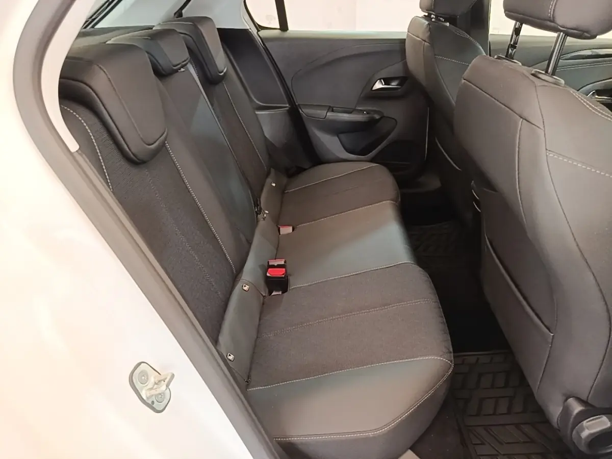 Vue intérieure côté gauche de la banquette arrière noire de l'Opel Corsa blanche, avec appuie-têtes et ceintures visibles.