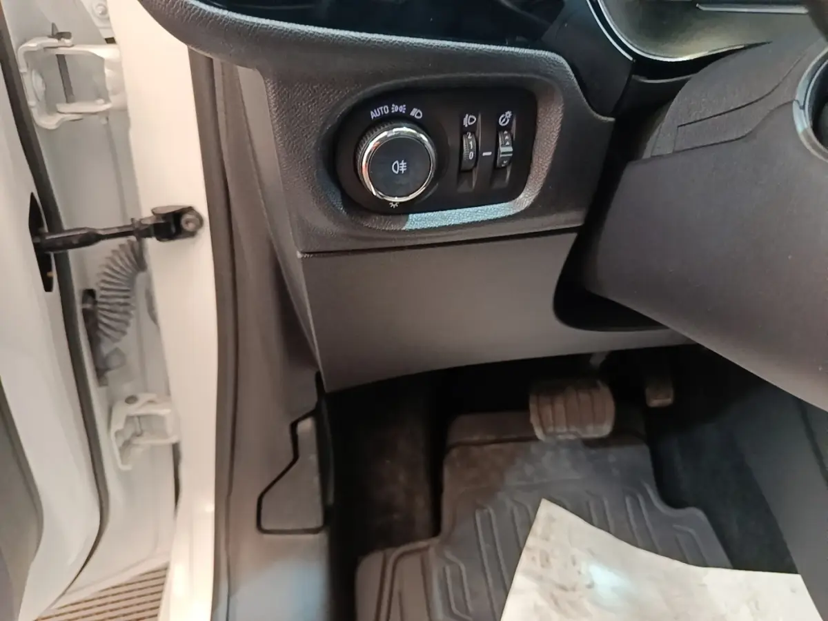 Détail intérieur côté gauche d'une Opel Corsa blanche 2022, avec commandes d'éclairage et pédale visible.