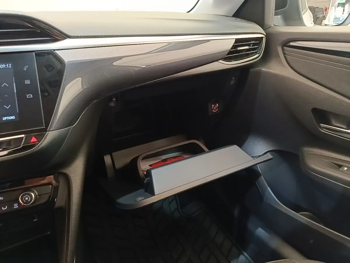 Intérieur de l’Opel Corsa 2022, vue côté passager sur la boîte à gants ouverte et tableau de bord noir.