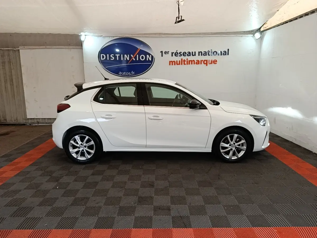 Vue latérale droite d'une Opel Corsa blanche 2022 avec jantes alliage et toit noir dans un showroom.