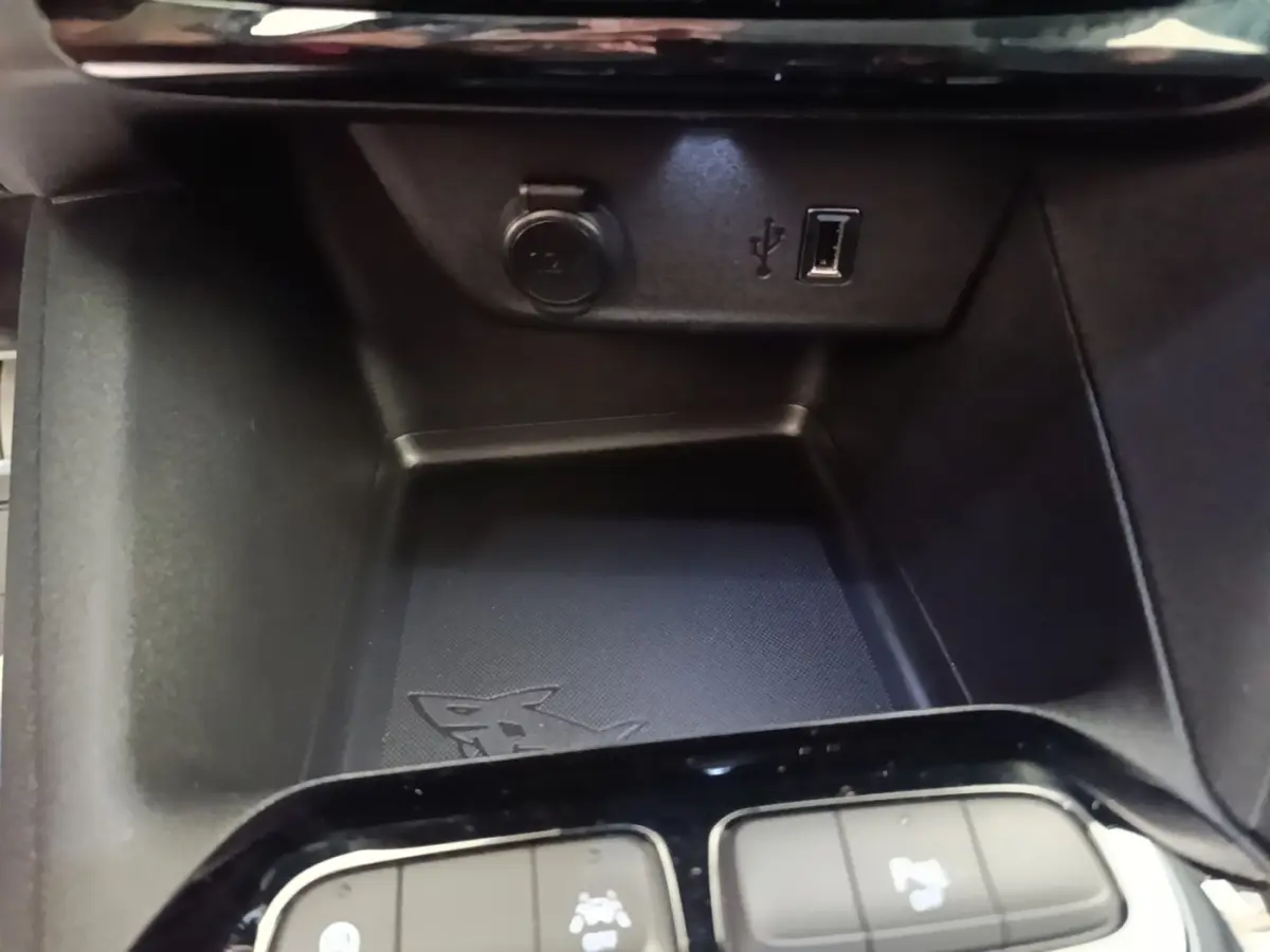 Gros plan sur la console centrale de l’Opel Corsa blanche, avec prise USB et prise 12V visibles.