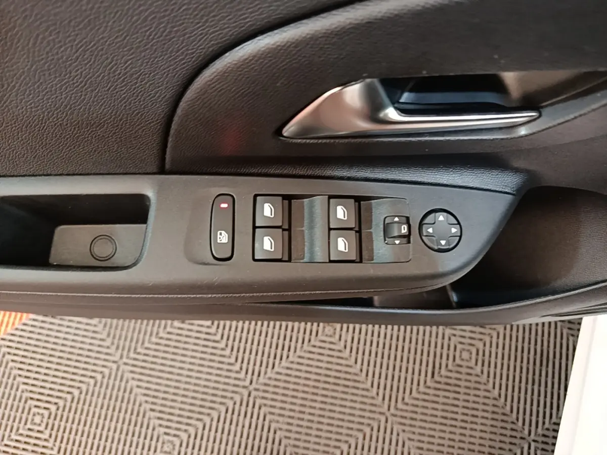 Vue rapprochée de la commande des vitres et des rétroviseurs sur la porte côté conducteur d'une Opel Corsa blanche.