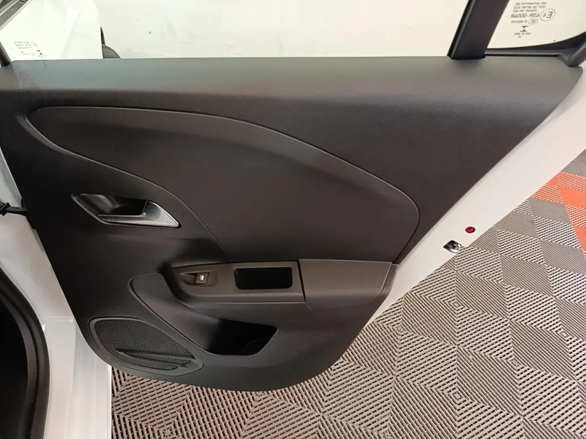 Vue intérieure de la porte avant gauche noire d'une Opel Corsa blanche, avec poignée argentée et commande de vitre.