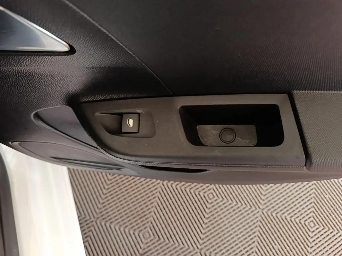 Gros plan sur la commande de lève-vitre côté conducteur d’une Opel Corsa blanche, intérieur noir.