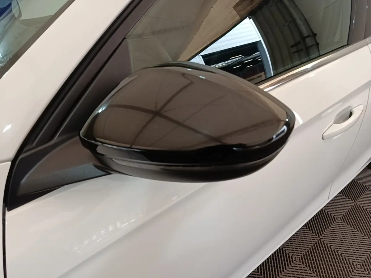 Gros plan sur le rétroviseur noir côté conducteur d'une Opel Corsa blanche vue de profil gauche.