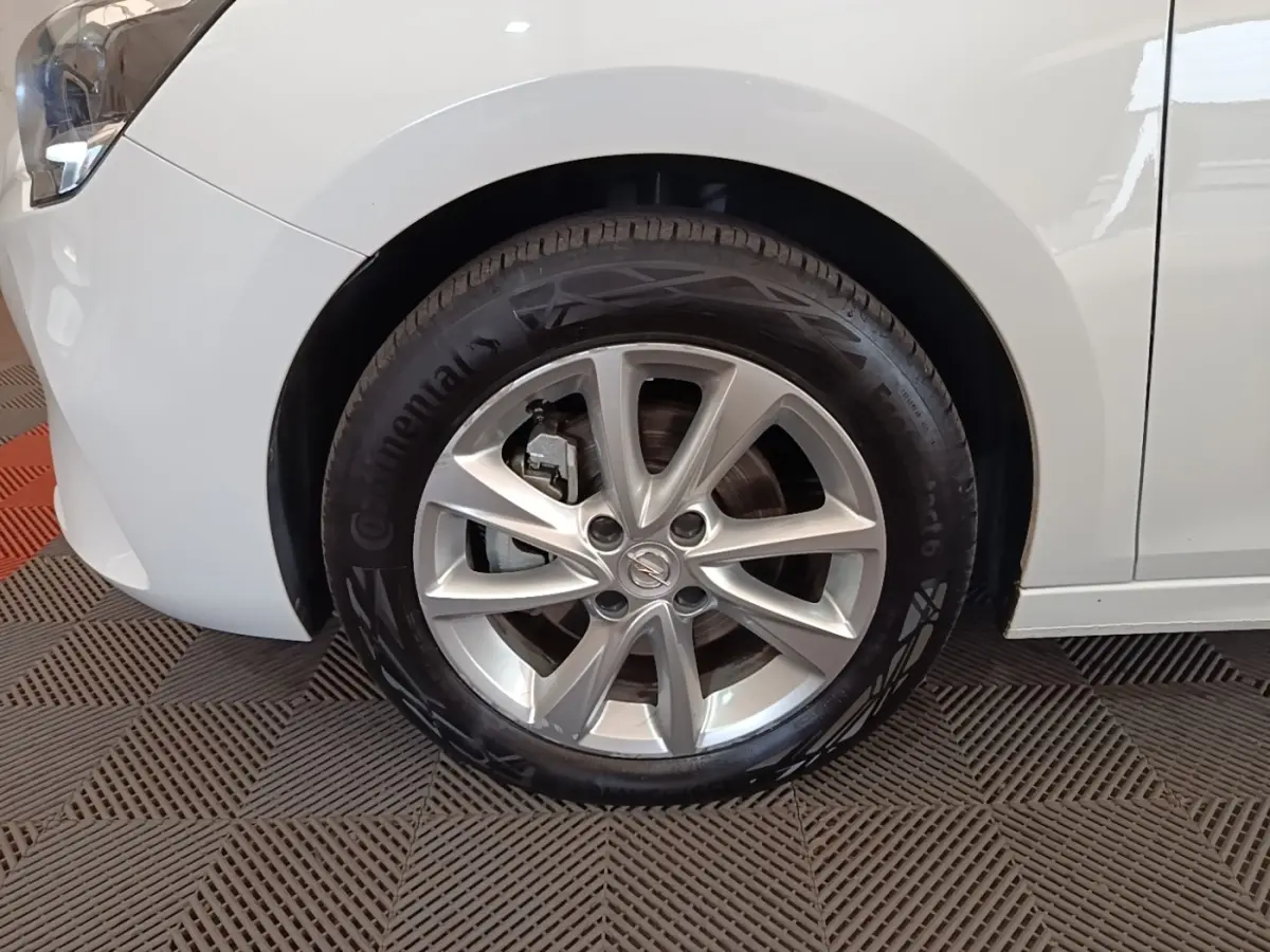 Gros plan sur la roue avant gauche d’une Opel Corsa blanche 2022 avec jante alliage et logo central Opel.
